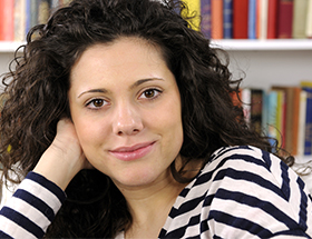 Beautiful Italian woman sitting by a bookshelf