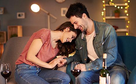 man and woman smiling at home drinking wine