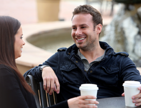 man and woman drinking coffee outside smiling