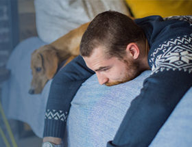 upset man on a bed with a dog