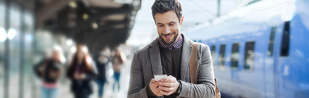 man looking at phone at train station