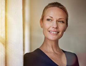 older woman looking out of window smiling