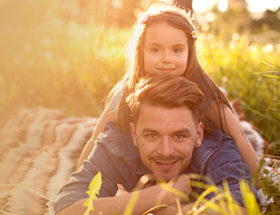 man and daughter lying in a field