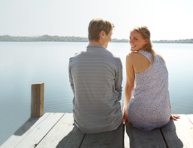 couple sitting on dock by the sea