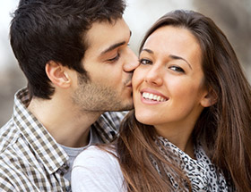 man kissing a smiling woman on the cheek