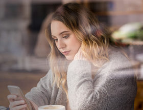 woman on her smartphone looking sad after being rejected